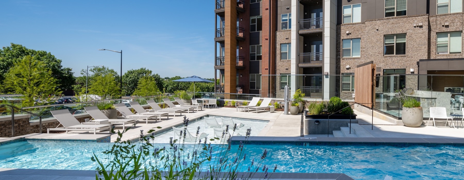 a courtyard with a pool, chairs and trees
